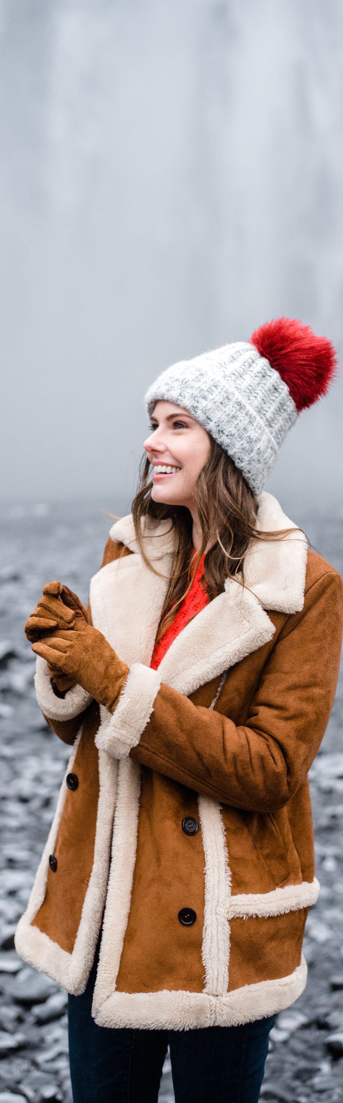 Alyssa Campanella of The A List blog visits Skogáfoss in South Iceland wearing Danner Cascade boots, Topshop faux shearling coat, and ASOS red cable knit sweater.